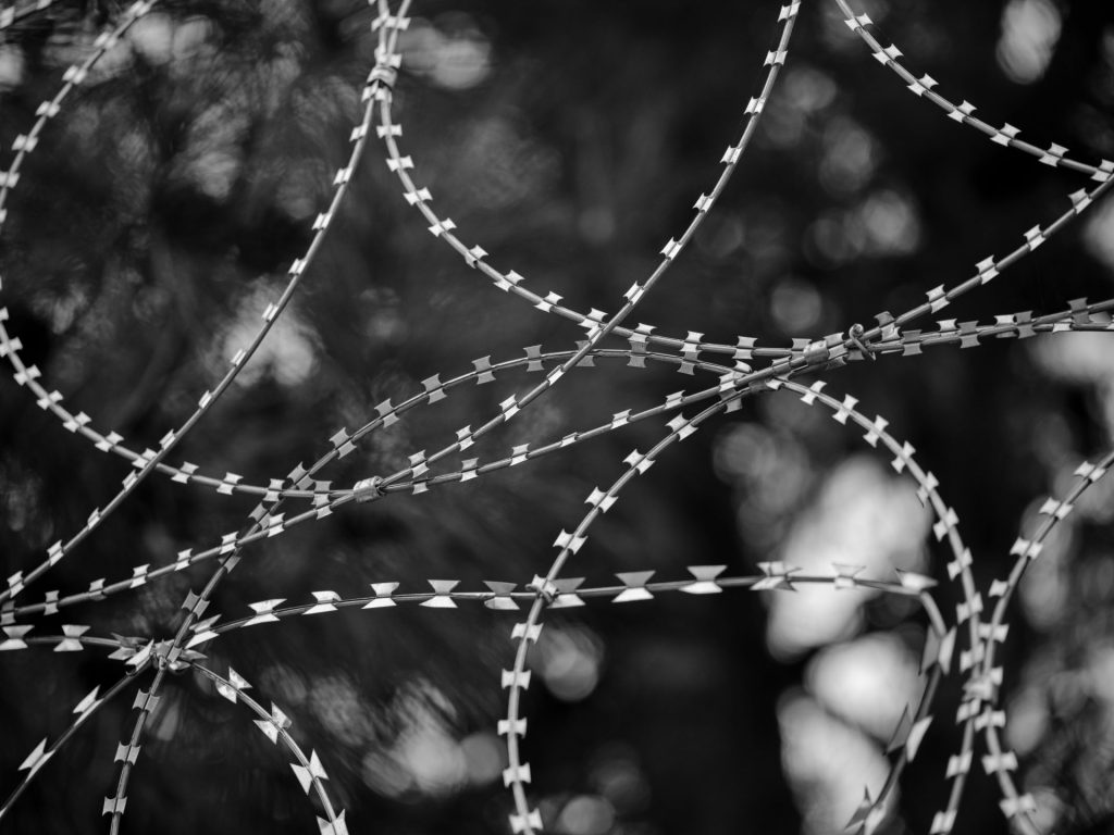 Artistic black and white close-up of twisting barbed wire coils with blurred background.